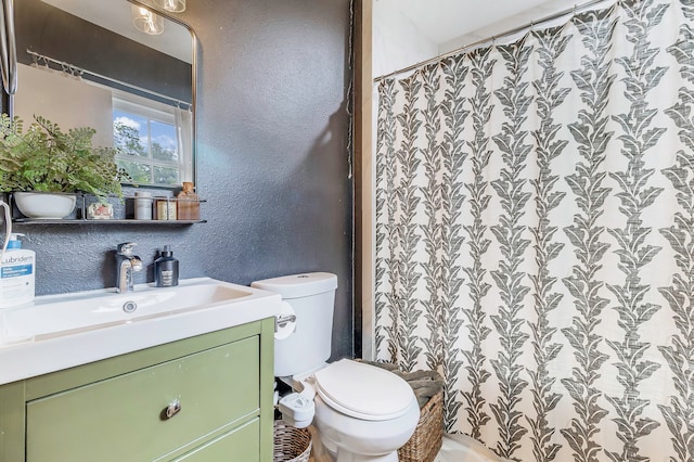 full bathroom featuring a shower with shower curtain, toilet, a textured wall, and vanity
