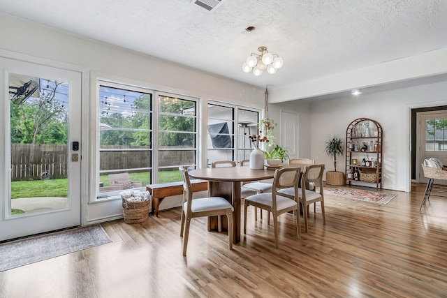 dining room featuring visible vents, wood finished floors, and a textured ceiling