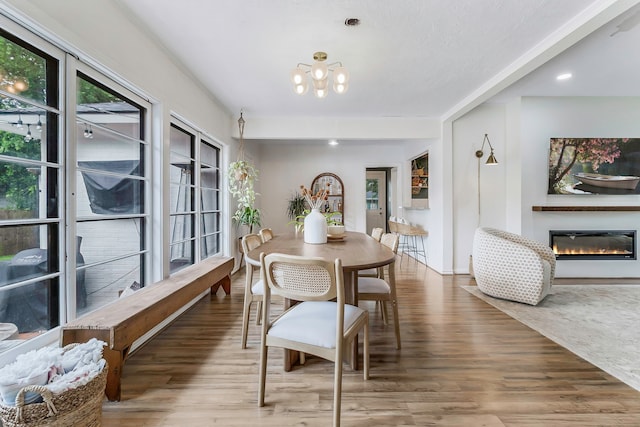 dining space featuring a glass covered fireplace, wood finished floors, and a chandelier