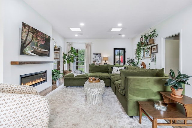 living area with recessed lighting, wood finished floors, a skylight, and a glass covered fireplace