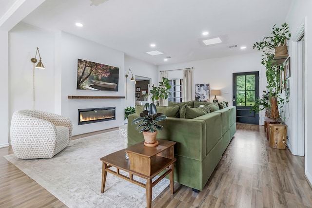 living room with recessed lighting, visible vents, wood finished floors, and a glass covered fireplace