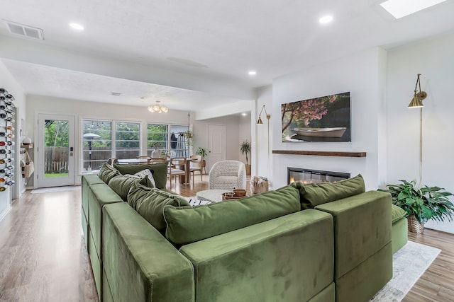 living room featuring a glass covered fireplace, visible vents, light wood-type flooring, and recessed lighting
