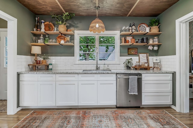 bar with wood finished floors, stainless steel dishwasher, decorative backsplash, and a sink