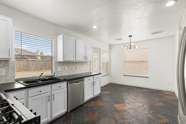 kitchen featuring a notable chandelier, dark countertops, dishwasher, and decorative backsplash