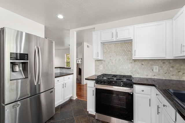 kitchen with gas range oven, white cabinets, stainless steel refrigerator with ice dispenser, and decorative backsplash