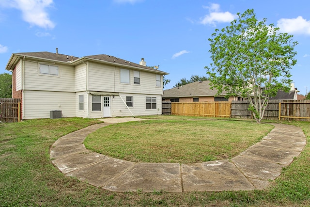 back of property with a chimney, a yard, central AC unit, and a fenced backyard