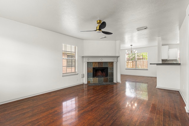 unfurnished living room featuring dark wood-style floors, visible vents, baseboards, and ceiling fan with notable chandelier