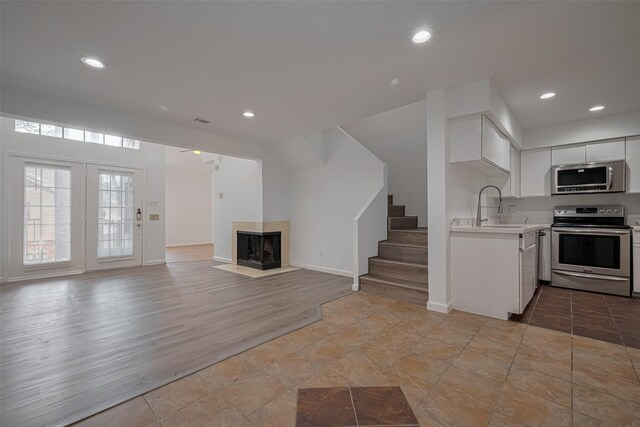 16800 Sugar Pines Dr Unit D28, Houston, TX 77090 - kitchen featuring stainless steel appliances, light countertops, a multi sided fireplace, a sink, and white cabinetry