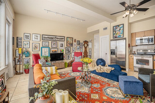 living room with a wealth of natural light, a ceiling fan, rail lighting, and visible vents