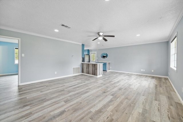 636 S Fm 356, Onalaska, TX 77360 - unfurnished living room with a textured ceiling, plenty of natural light, a ceiling fan, light wood-type flooring, and visible vents