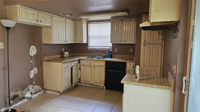 kitchen with cream cabinets, light tile patterned floors, black dishwasher, light countertops, and a sink