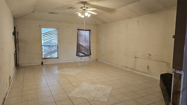 unfurnished room with baseboards, ceiling fan, a textured ceiling, and light tile patterned flooring