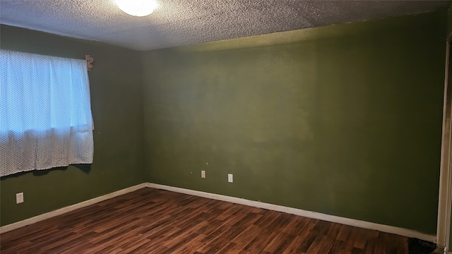 empty room featuring dark wood finished floors, baseboards, and a textured ceiling