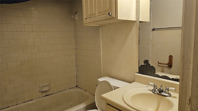 full bath with toilet, vanity, a textured wall, and tub / shower combination