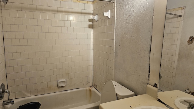 full bath with tub / shower combination, toilet, a textured wall, and vanity