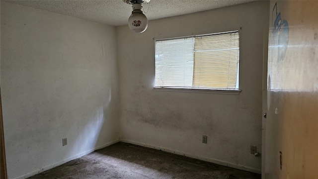carpeted empty room featuring a textured ceiling and baseboards