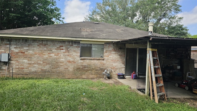 back of house with a lawn, brick siding, and roof with shingles