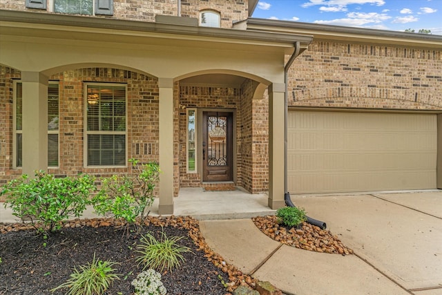 view of exterior entry with brick siding, concrete driveway, and an attached garage