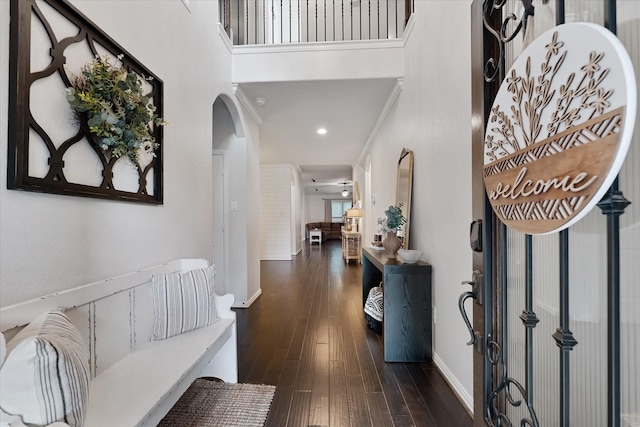 foyer entrance with arched walkways, dark wood-style floors, a towering ceiling, and recessed lighting