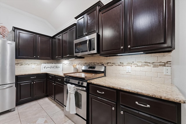 kitchen featuring appliances with stainless steel finishes, ornamental molding, vaulted ceiling, light tile patterned flooring, and tasteful backsplash