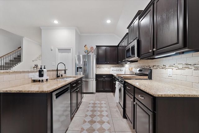 kitchen with appliances with stainless steel finishes, a sink, backsplash, crown molding, and a kitchen island with sink