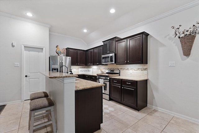 kitchen featuring appliances with stainless steel finishes, a sink, tasteful backsplash, a kitchen breakfast bar, and crown molding