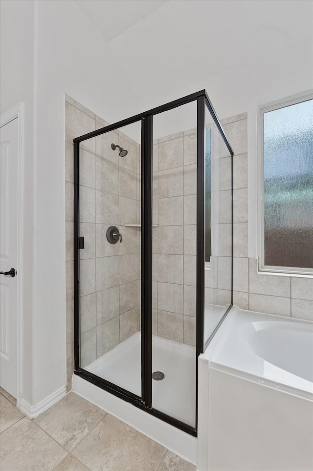 full bathroom with a shower stall, a bath, and tile patterned floors