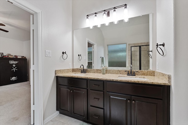 bathroom featuring a ceiling fan, tiled shower, and double vanity