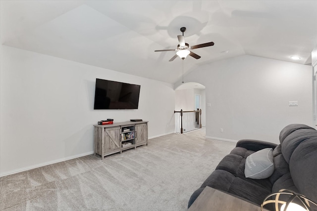 living area featuring a ceiling fan, lofted ceiling, light colored carpet, baseboards, and arched walkways