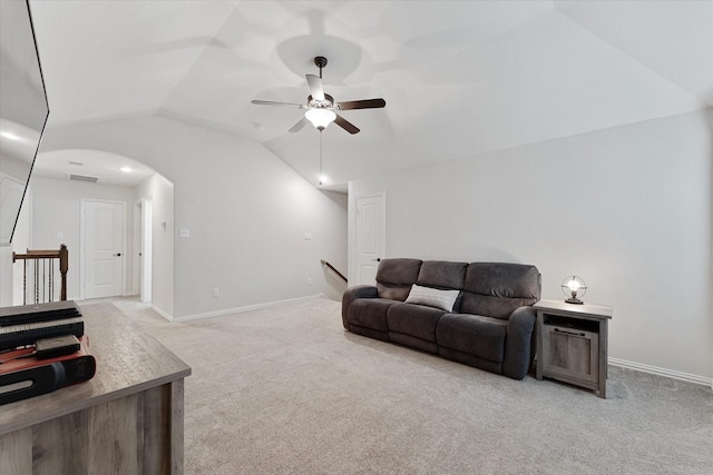 living area featuring vaulted ceiling, a ceiling fan, light colored carpet, arched walkways, and baseboards