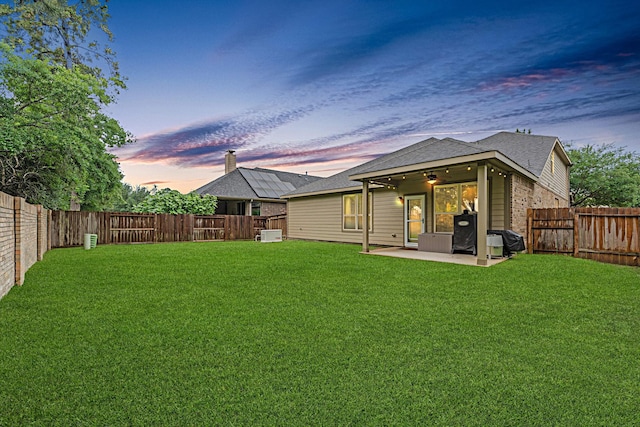 back of house at dusk featuring a patio area, ceiling fan, roof with shingles, and brick siding