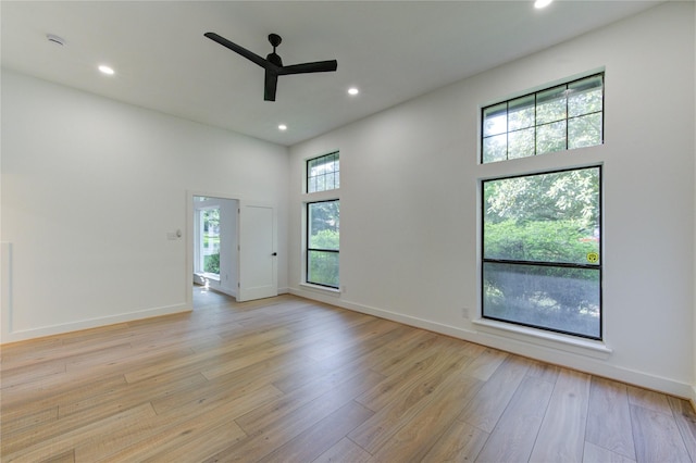 empty room featuring recessed lighting, a ceiling fan, a high ceiling, and light wood-style flooring