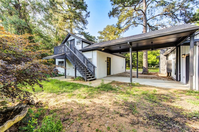 exterior space featuring stairway, a carport, a wooden deck, and roof with shingles