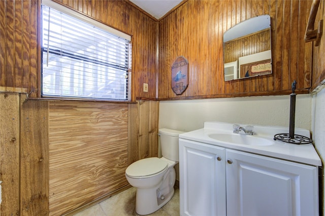 half bathroom featuring wood walls, toilet, tile patterned flooring, and vanity