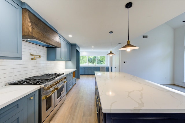 kitchen with decorative backsplash, light wood-style flooring, custom range hood, a center island, and range with two ovens