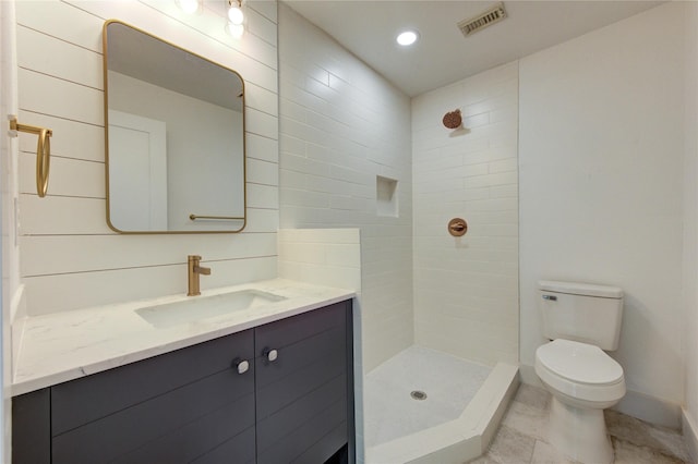 bathroom featuring visible vents, tiled shower, toilet, and vanity