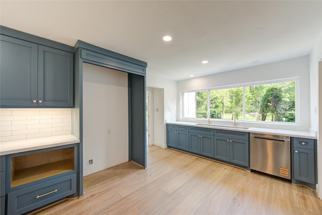 kitchen with a sink, decorative backsplash, light wood-style flooring, light countertops, and stainless steel dishwasher