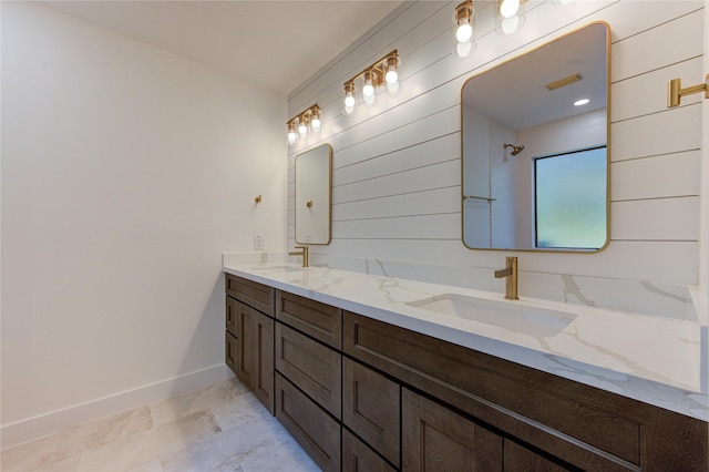 full bathroom featuring double vanity, walk in shower, baseboards, and a sink