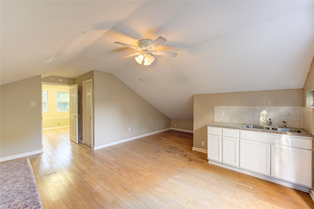 additional living space featuring lofted ceiling, a sink, ceiling fan, baseboards, and light wood finished floors