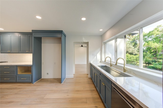 kitchen featuring light wood-style flooring, a sink, a wealth of natural light, and decorative backsplash