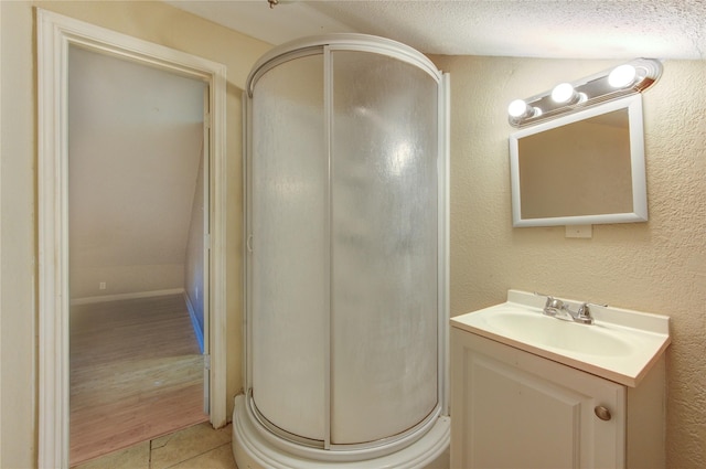 bathroom featuring a textured ceiling, vanity, a shower stall, and tile patterned flooring