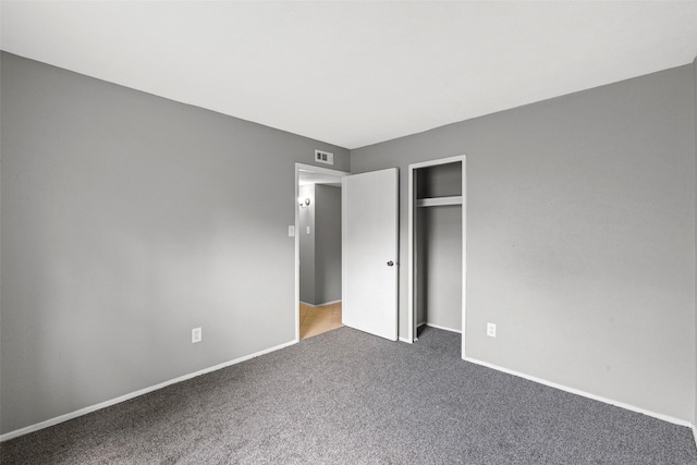 unfurnished bedroom with a closet, visible vents, carpet floors, and baseboards