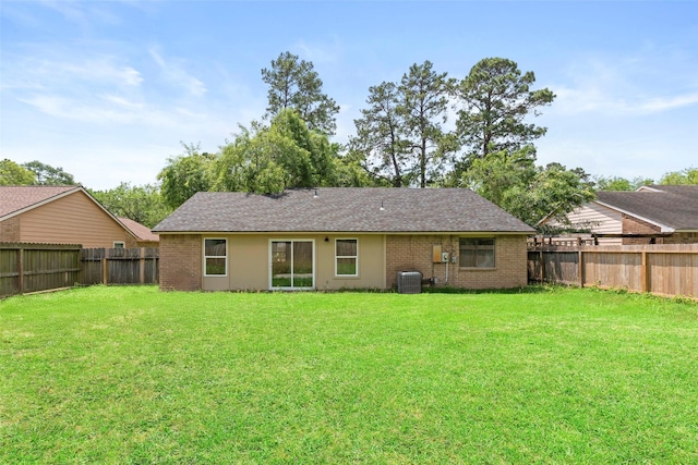 rear view of house featuring cooling unit, a yard, a fenced backyard, and brick siding
