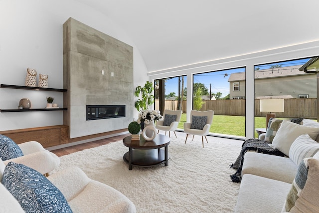 living room featuring vaulted ceiling, wood finished floors, and a fireplace