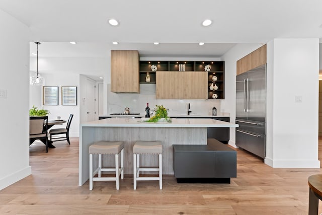 kitchen with light countertops, modern cabinets, open shelves, and stainless steel built in refrigerator