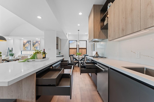 kitchen with light stone countertops, light wood finished floors, a center island, stainless steel appliances, and modern cabinets