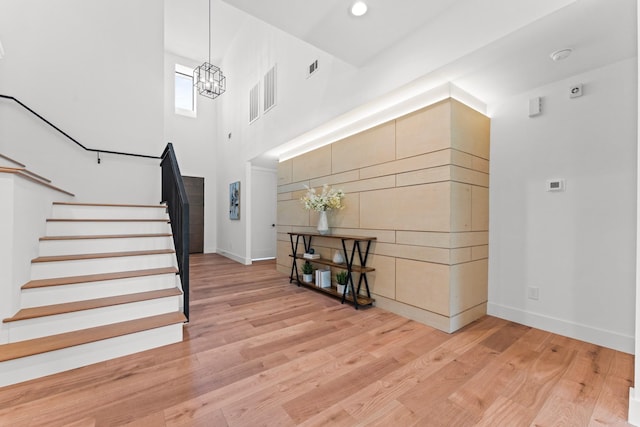 entryway featuring stairs, baseboards, a chandelier, and light wood-style floors