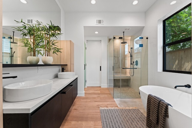 bathroom with visible vents, a freestanding tub, a shower stall, a sink, and recessed lighting