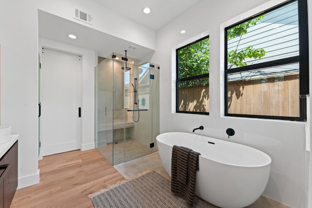 full bath with vanity, visible vents, wood finished floors, a soaking tub, and a shower stall