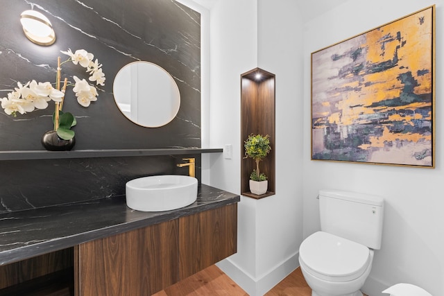 bathroom with toilet, baseboards, wood finished floors, and vanity